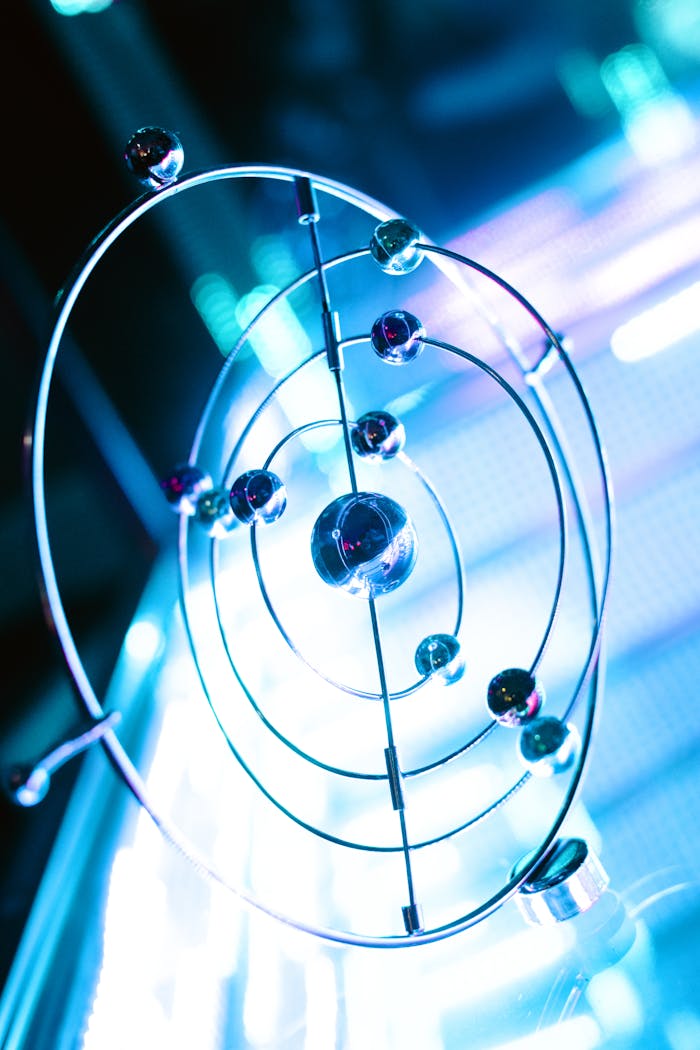 A futuristic metal orbital sculpture illuminated by neon lights creating a vibrant visual effect.